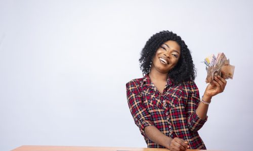 A confident black lady sitting and holding a wad of cash on an isolated background