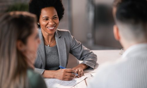 Happy African American financial advisor giving consultations to a couple while making their future investment plans.