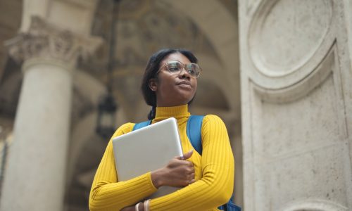 portrait of young woman with laptop in hands outside a school